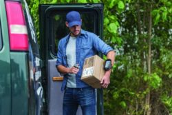 man scanning box with mobile handheld computer outside by his van