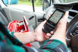 man in van holding rugged smartphone with scanner and extra battery pack