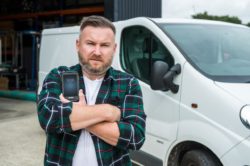 man in front of van holding rugged smartphone with scanner